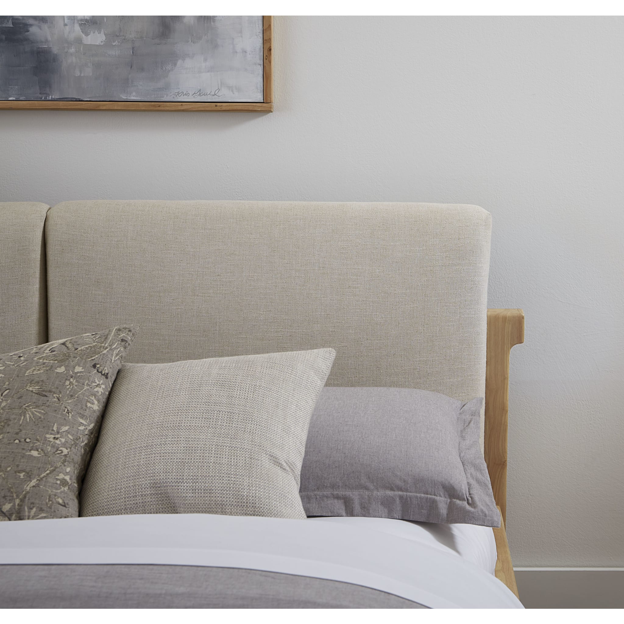 Front view of the Havn platform bed featuring a ginger-finished ash wood frame and a two-cushion natural linen headboard