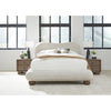 Lifestyle shot featuring the Afra bed styled with neutral bedding and wood nightstands in a bright industrial-style bedroom
