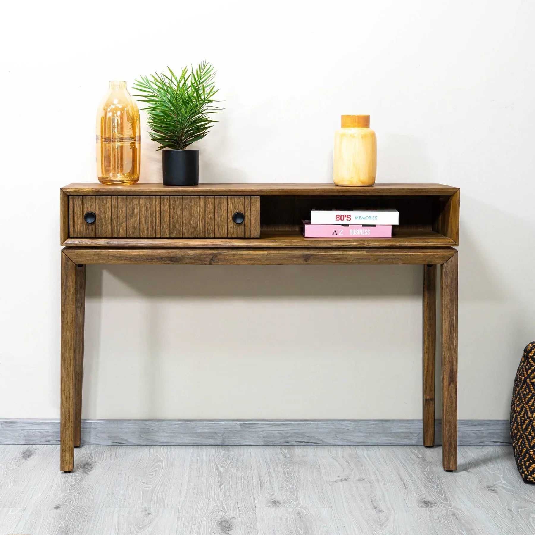 Front view of the West console table in a rich wood finish featuring a slim architectural frame, an integrated drawer with fluted texture, and an open storage cubby