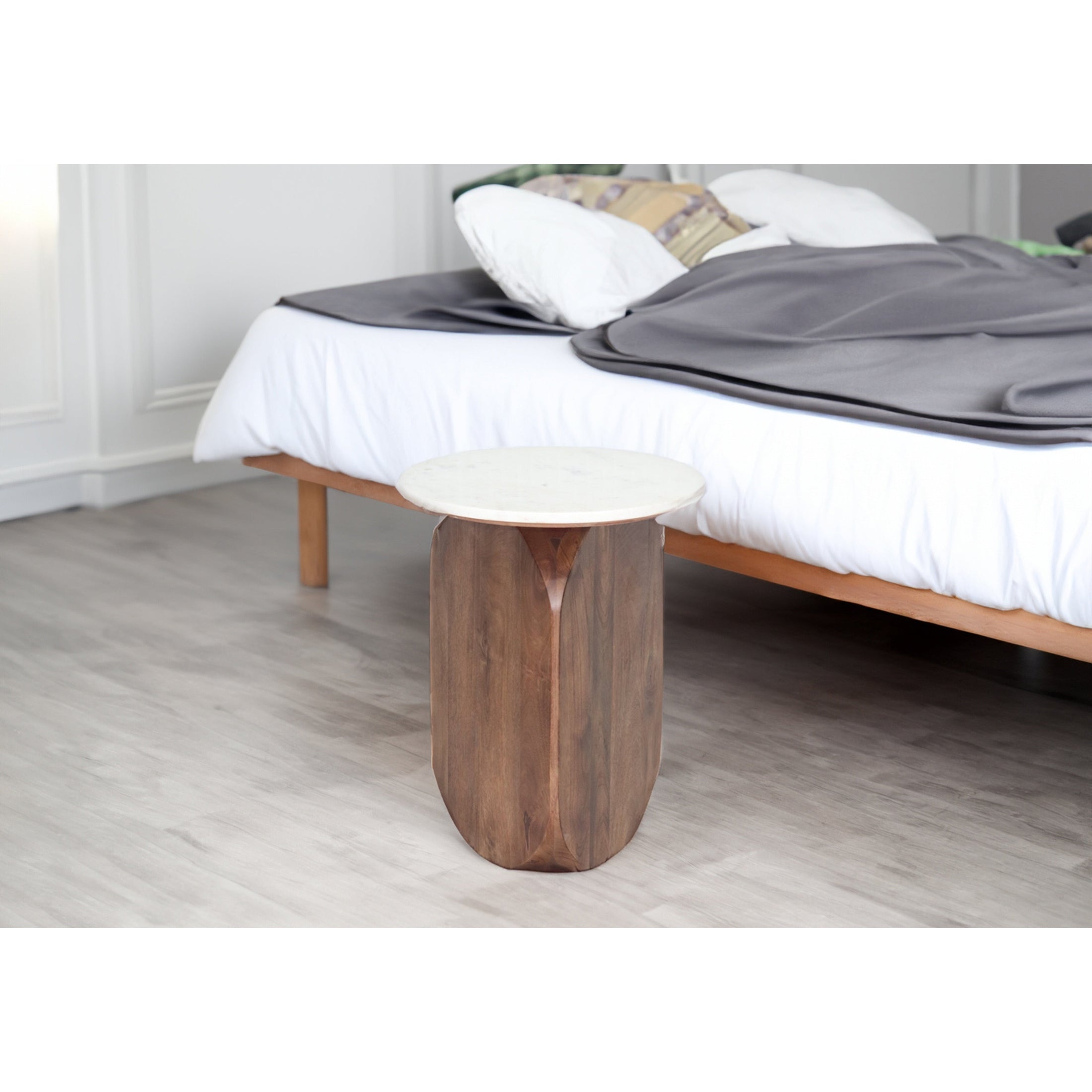 High-angle perspective view of the Abelone side table featuring a circular white marble top and a chunky dark wood pedestal base with vertical carved details