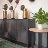 Lifestyle shot featuring the Spiral sideboard styled with gold vases and natural greenery in a bright contemporary interior
