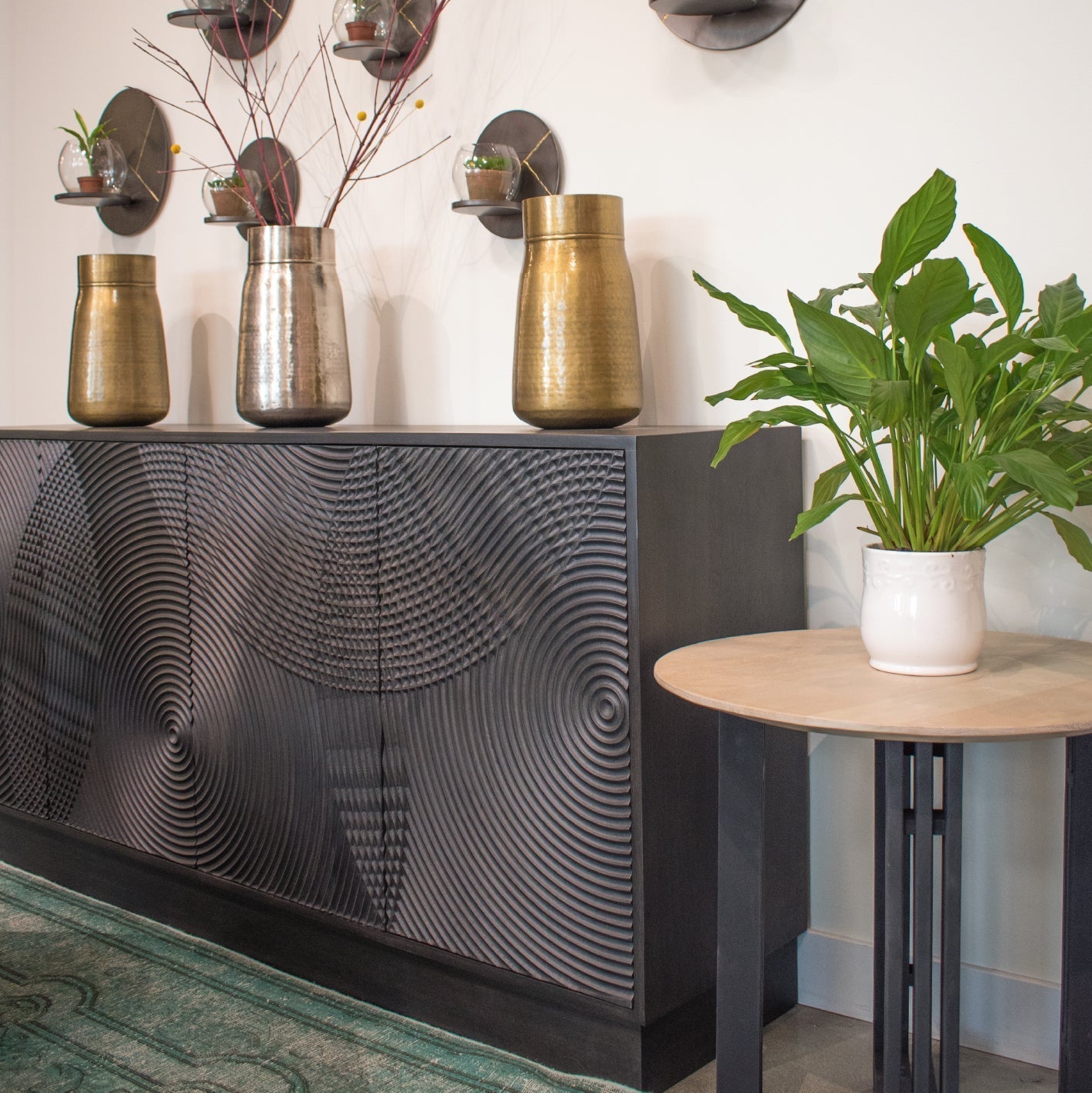 Three-quarter perspective view of the Spiral sideboard featuring a matte black finish and intricate circular relief carvings across four doors