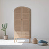 Lifestyle shot featuring the Arco tall cabinet in a bright minimalist room styled with a potted cactus and woven floor baskets