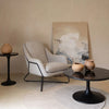 Wide lifestyle shot demonstrating the table's scale in a modern living room paired with a grey textured armchair and minimalist art