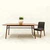 Front view of the table styled with a white planter and a single grey upholstered chair against a white background