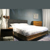 Lifestyle perspective of the bed styled in a moody master suite with dark blue walls and a matching acacia dresser