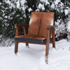 The Rio armchair photographed outdoors in a snowy landscape to emphasize its rustic organic materials