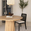 Lifestyle perspective of the natural oak table styled with a contrasting black rattan back dining chair