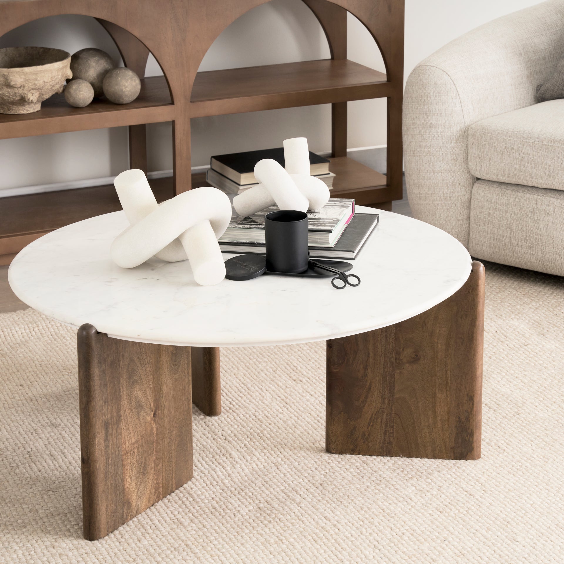 Close-up lifestyle shot of the Rumer marble coffee table styled with decorative objects on a neutral area rug