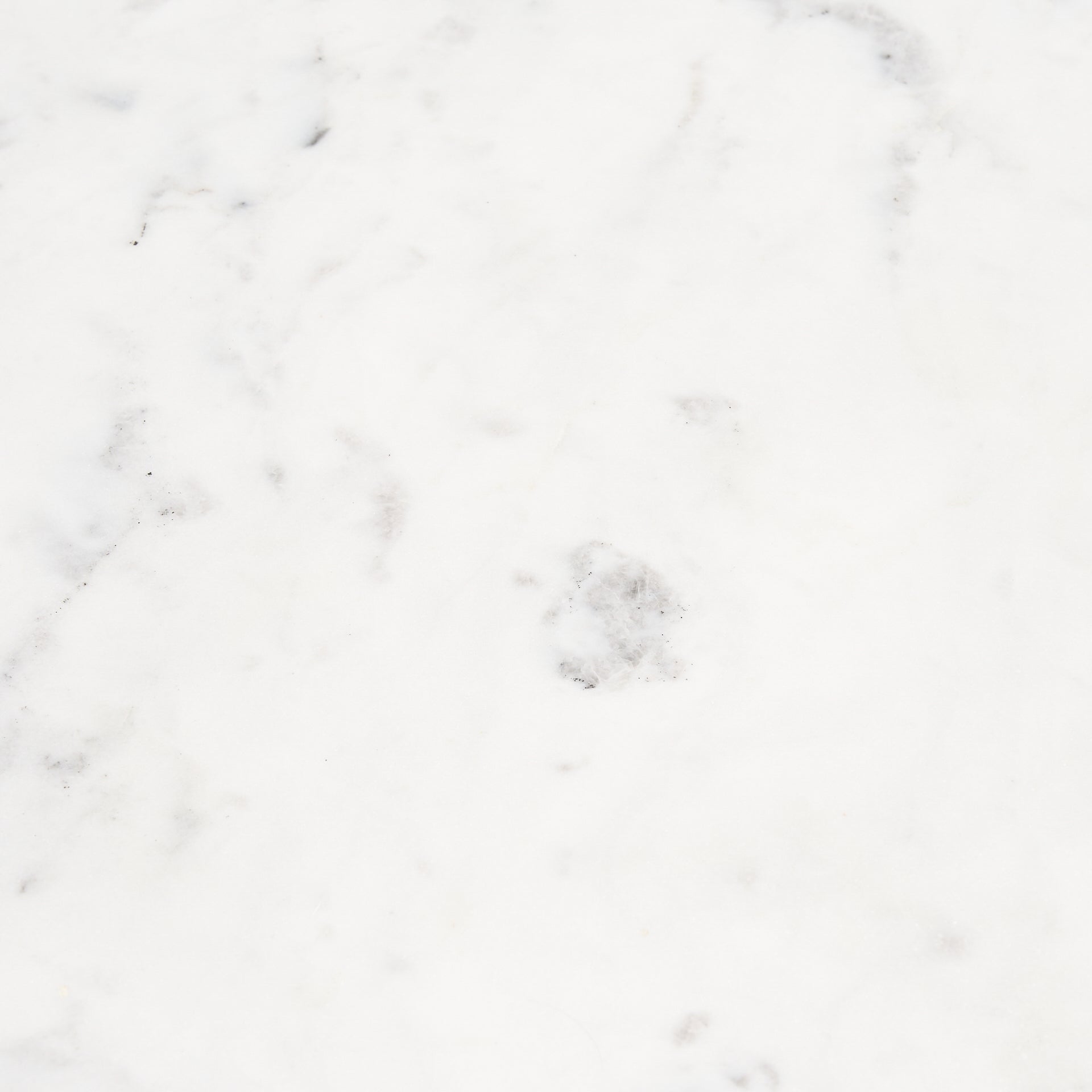 Macro detail shot focusing on the natural grey veining and polished finish of the Rumer white marble tabletop
