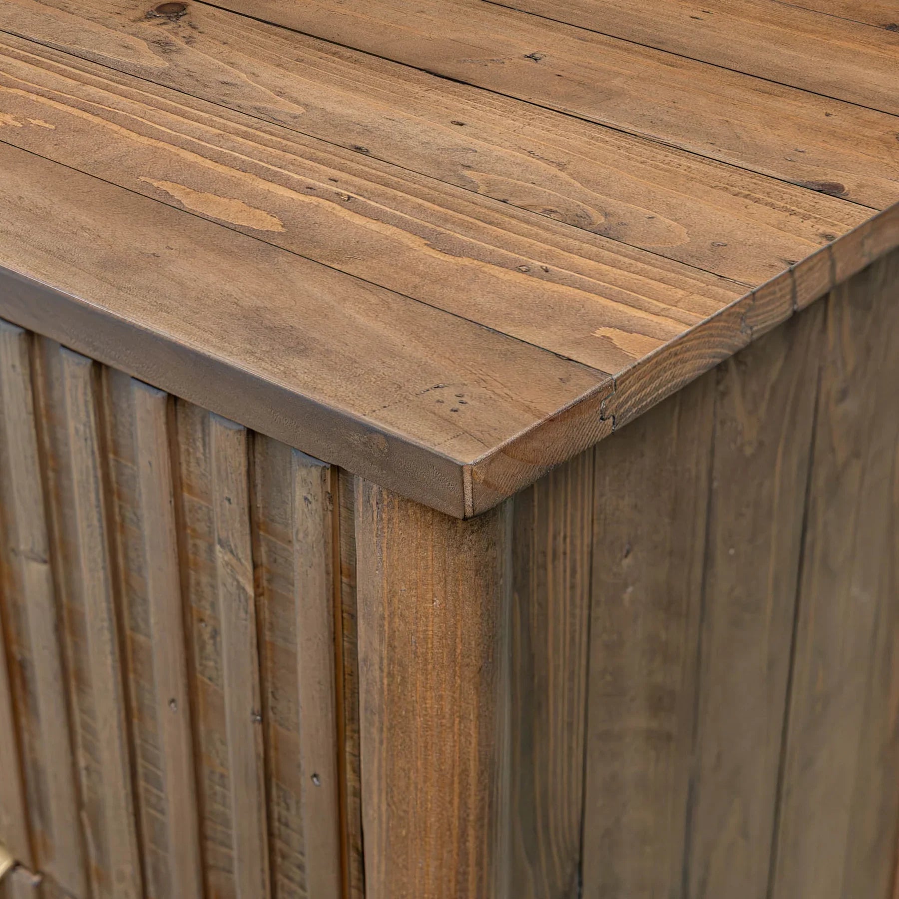 Front view of the Britanica 5-drawer chest featuring a warm rustic brown finish with vertical fluted wood textures and sleek gold metal handles