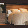 Perspective detail of the plank headboard styled with warm tan linens and matching wood nightstands