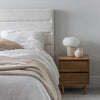 Lifestyle perspective showcasing the cream fabric bed in a soft minimalist room setting with natural wood accents
