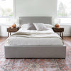 Wide lifestyle shot featuring the Julia bed styled on a vintage-patterned rug with mid-century modern bedside tables
