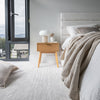Wide lifestyle shot highlighting the low-profile headboard design in a warm airy master bedroom setting