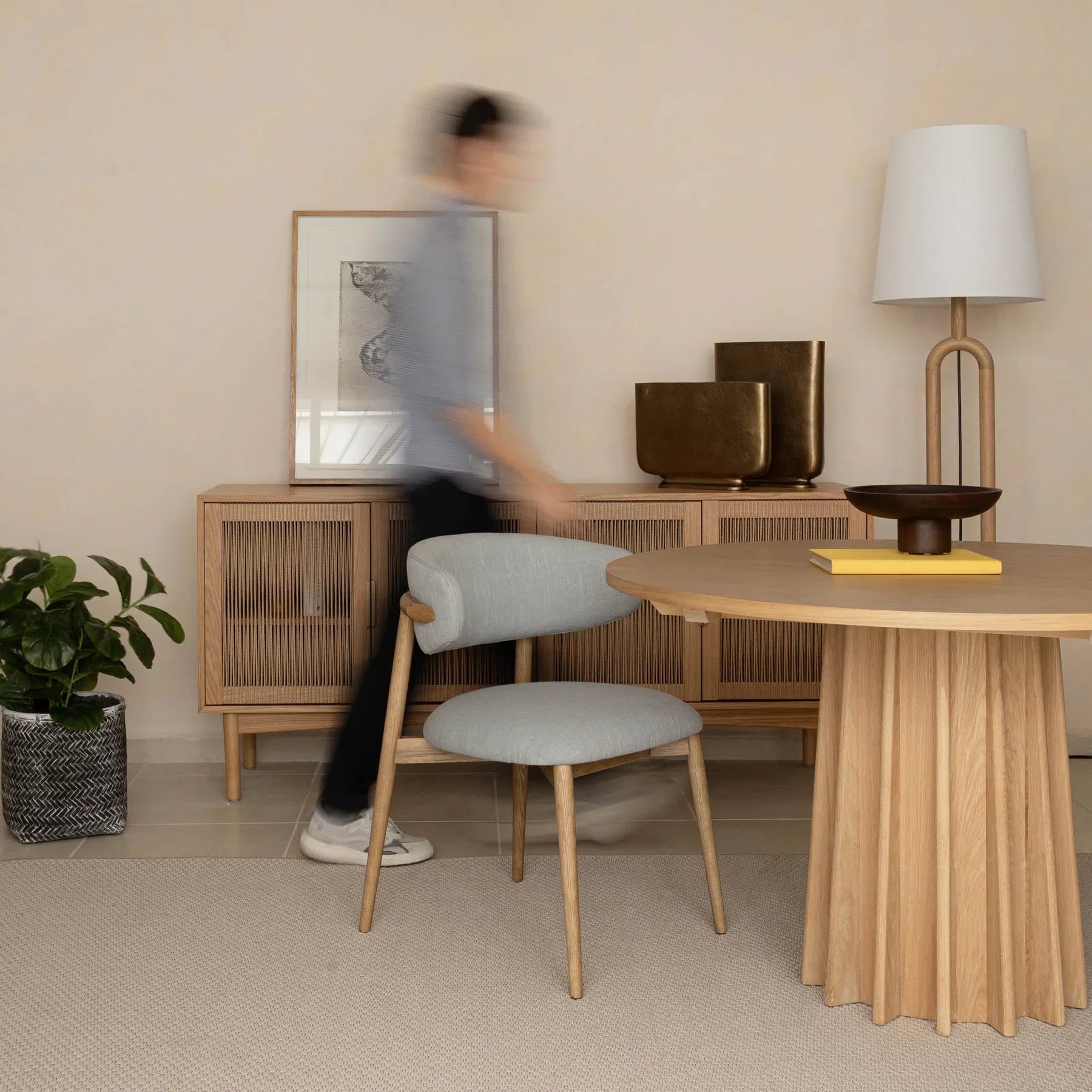 Front view of the Sculpture round dining table featuring a natural oak finish and a striking fluted pedestal base
