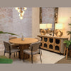 Lifestyle shot featuring the round oak table fully styled with four upholstered chairs and a decorative sideboard