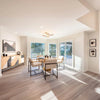 Wide-angle lifestyle shot of the table in a sunlit open-concept dining area with large windows