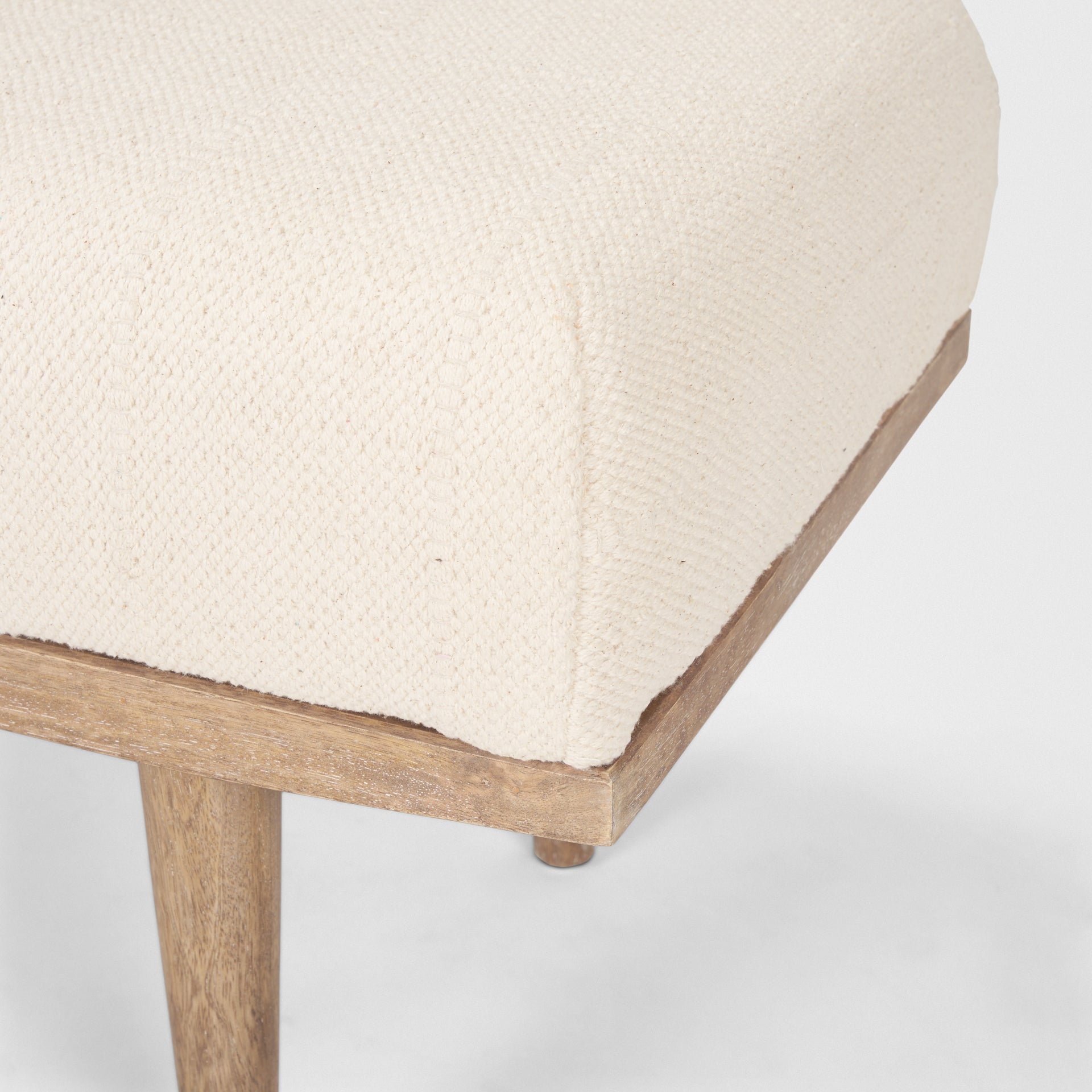 Front view of the Shae bench featuring a plush oatmeal-colored upholstered seat and a tapered brown wood frame