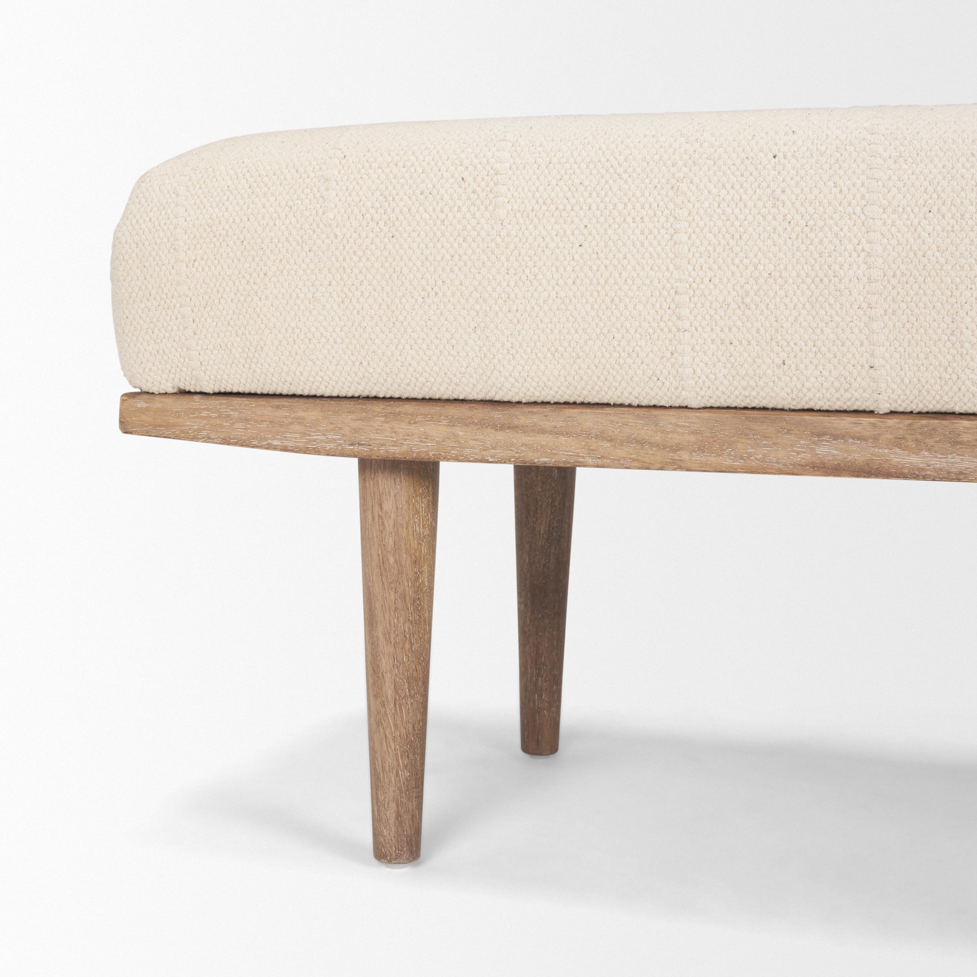 Front view of the Shae bench featuring a plush oatmeal-colored upholstered seat and a tapered brown wood frame