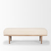 Front view of the Shae bench featuring a plush oatmeal-colored upholstered seat and a tapered brown wood frame