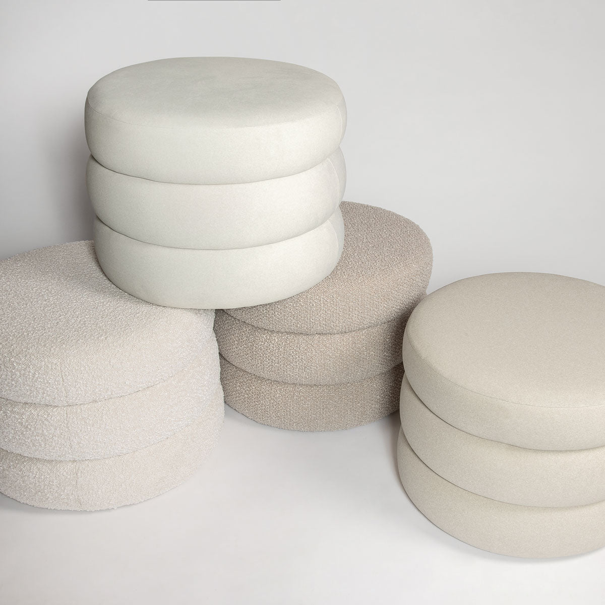 Group shot of the Siel ottoman collection showcasing various neutral velvet tones and stacked silhouettes in a studio setting