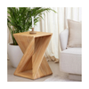 Lifestyle shot of the sculptural wood table styled in a bright minimalist room next to a white upholstered sofa and potted plant
