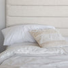 Lifestyle shot featuring the headboard corner styled with plush white pillows and a decorative textured cushion