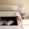 Close-up of the headboard corner styled with a white ribbed ceramic lamp and a green accent nightstand