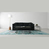 Lifestyle shot featuring the Sona nesting tables centered in a minimalist room with a black sofa and a teal patterned rug