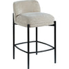 Angled view of the Sorte counter stool featuring cream upholstery and black metal legs