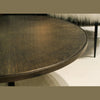 Close-up shot highlighting the intricate sunburst wood grain pattern and the textured bronze edge of the circular tabletop