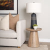Lifestyle shot demonstrating the table used as a functional side piece paired with a modern armchair and lamp