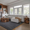 Lifestyle shot featuring a Natura Opus teak root table styled in a contemporary living room with a neutral sectional sofa