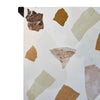 Macro shot showcasing the unique earth-toned stone inlay patterns within the polished white terrazzo tabletop