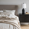 Close-up lifestyle shot featuring the Faye headboard styled with a modern black nightstand and a minimalist table lamp