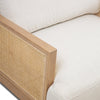 Close-up of the smooth solid oak armrest and the intricate woven cane side panel on the Unio chair.