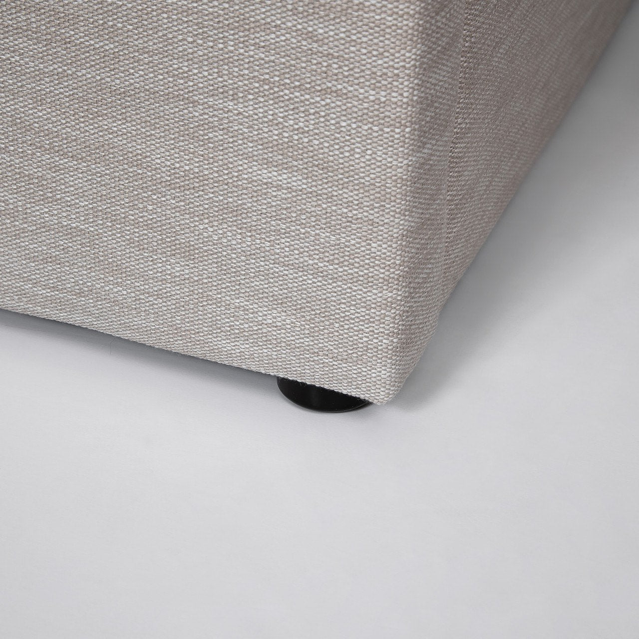 Detailed view of the seamless bed frame corner highlighting the high-quality sand fabric weave and plush cushioning