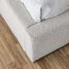 Close-up view of the bed frame corner highlighting the clean tailoring and the natural wood base trim