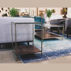 Lifestyle shot featuring the Venus table styled next to a grey fabric armchair on a blue patterned area rug