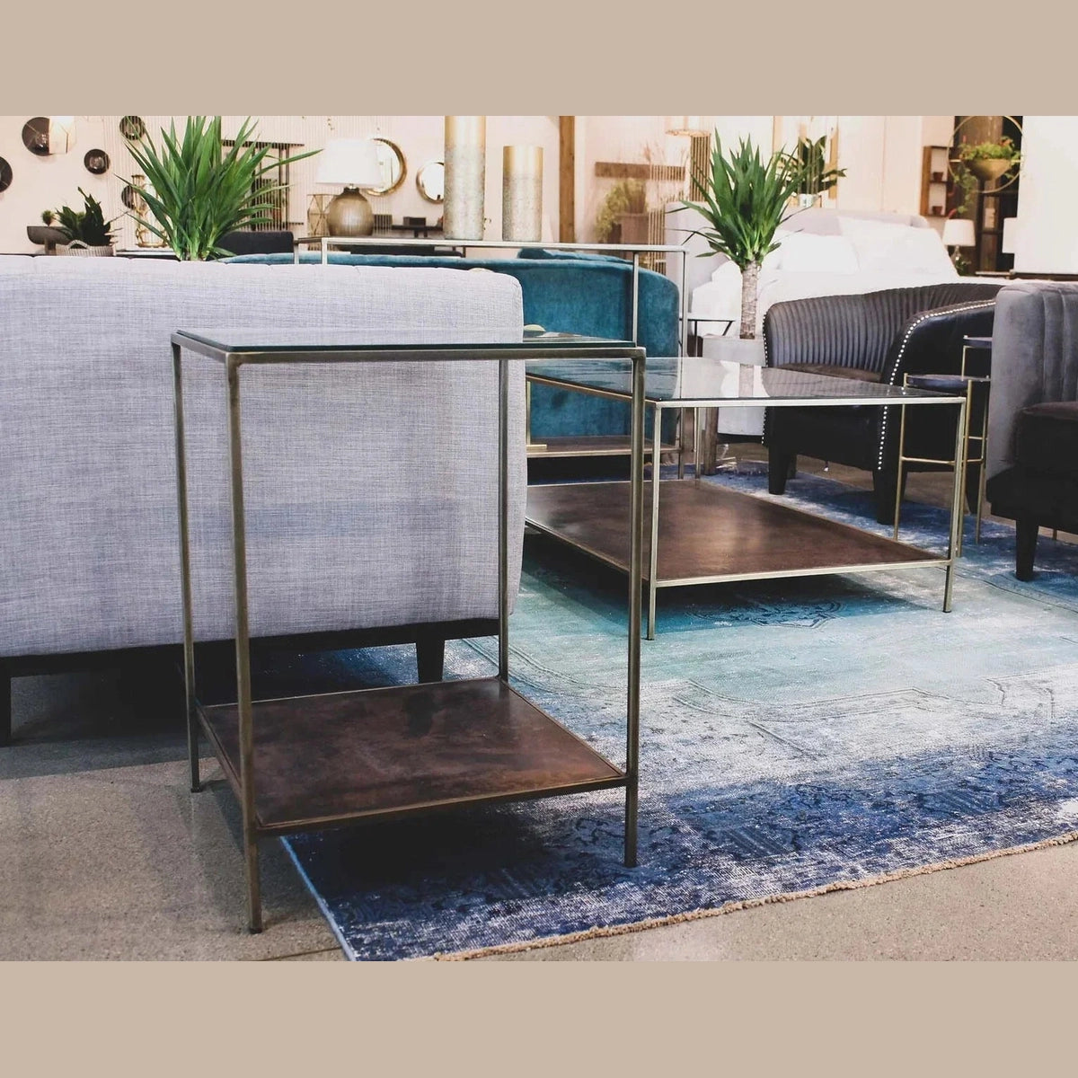 Three-quarter view of the Venus side table featuring a clear square glass top and a minimalist antique brass frame with a solid lower shelf