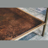 Detail shot showing the precision joinery where the clear glass top meets the slim antique brass metal support