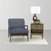 Studio lifestyle view showcasing the nightstand used as a side table next to a contemporary navy blue armchair