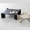 Lifestyle shot featuring the Vito coffee table paired with a woven accent chair in a clean modern interior