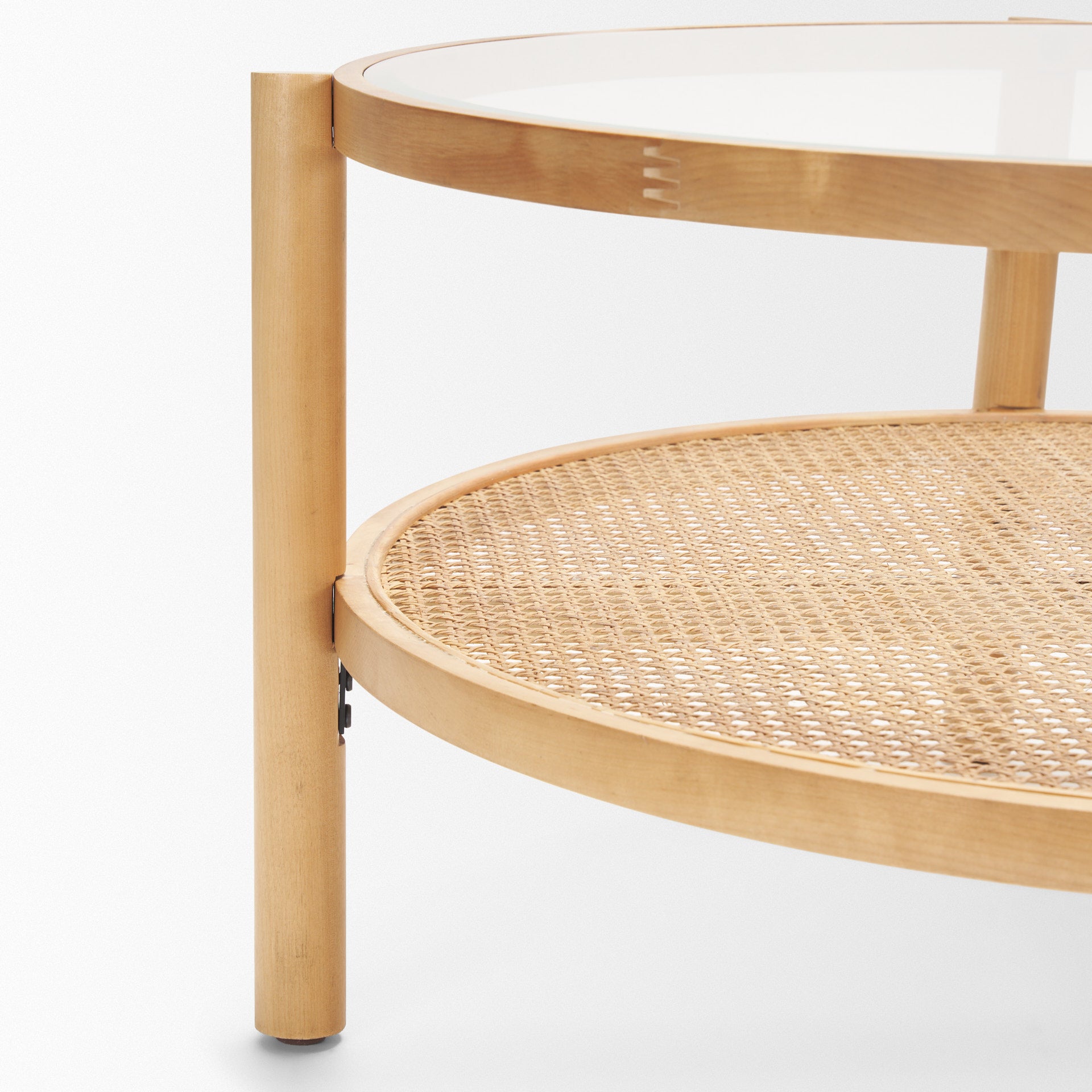Front view of the Weslyn coffee table featuring a circular glass top and a natural woven cane lower storage shelf