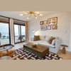 Lifestyle shot of the West coffee table centered on a geometric rug in a bright, contemporary living space
