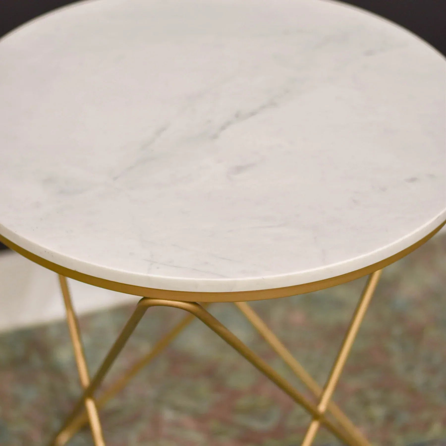 Front view of the Earth Wind and Fire side table featuring a circular white marble top and a sculptural gold-finished geometric wire base