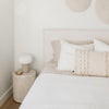 Lifestyle shot featuring the white wood stump used as a minimalist nightstand in a neutral bedroom setting