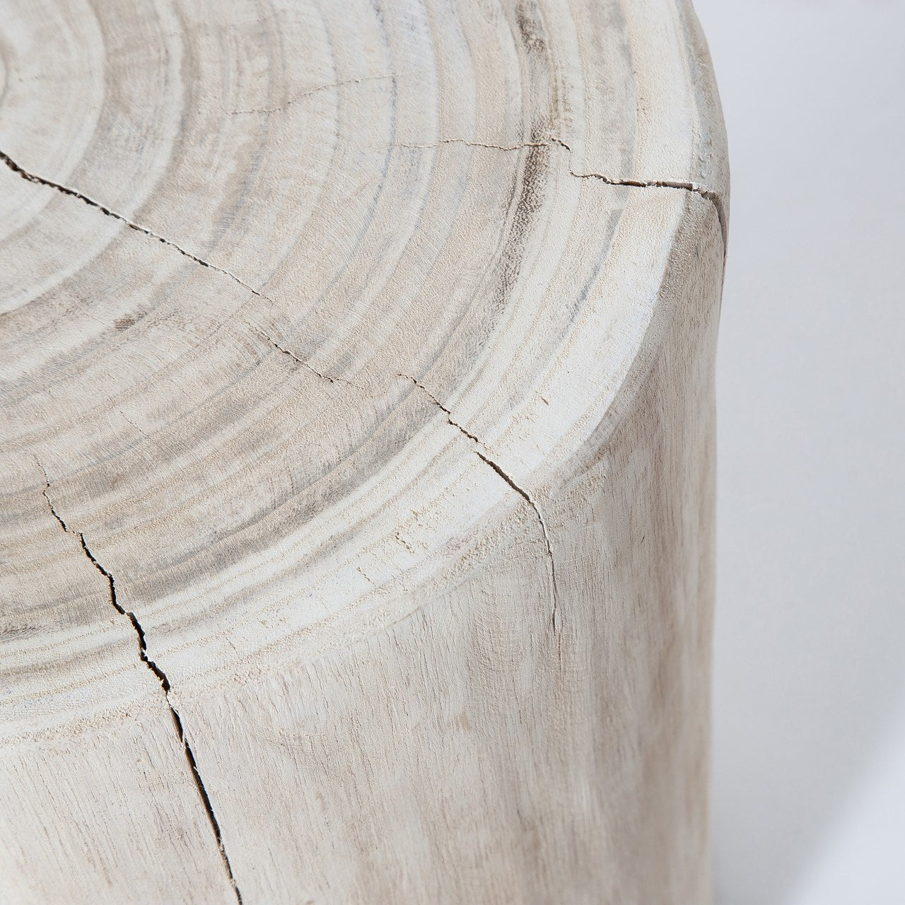 Macro shot focusing on the rustic textured surface and white wash finish of the solid wood stump side table