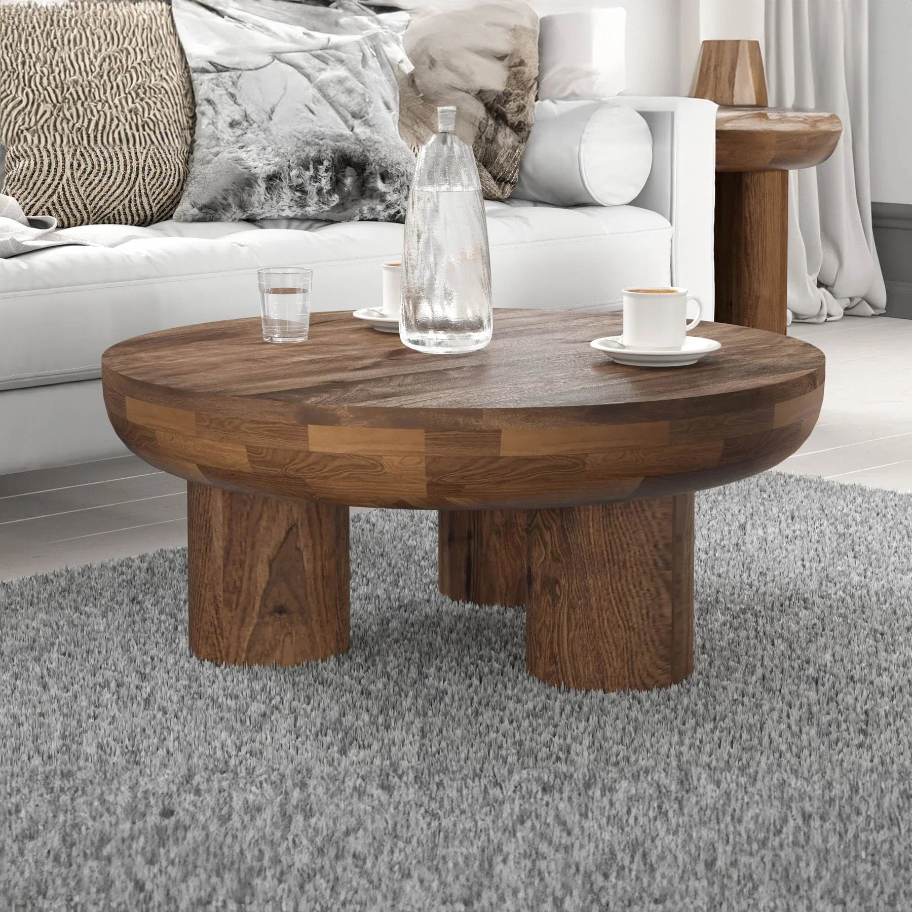 Front view of the Wilder round coffee table featuring a thick solid wood top and three chunky cylindrical pedestal legs
